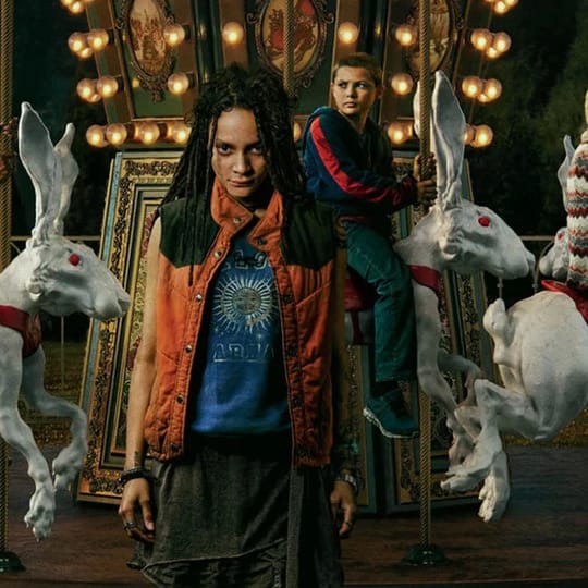 A girl stands in front of a carousel with people riding rabbits