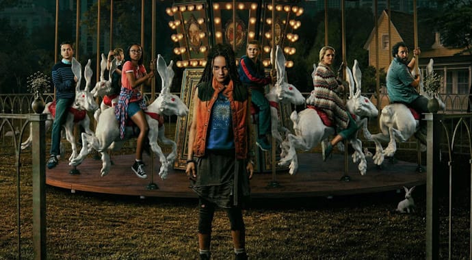 A girl stands in front of a carousel with people riding rabbits