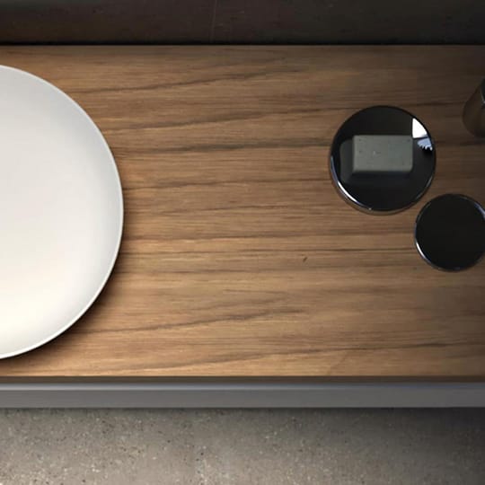 A top-down view of a white oval sink with a wood surround