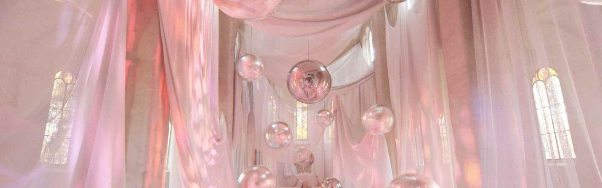 A visualization of a pink hued chapel with disco balls and reflective globes inside