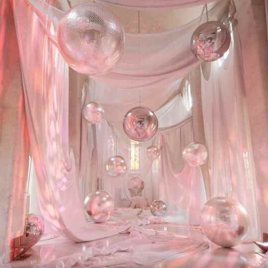 A visualization of a pink hued chapel with disco balls and reflective globes inside