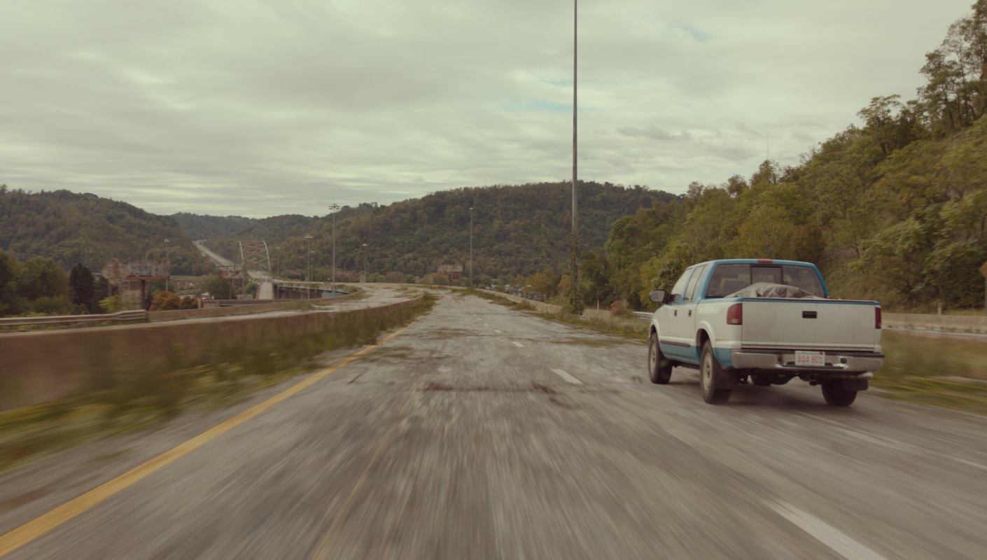 Blue and white truck speeds down a decaying highway in 'The Last of Us'