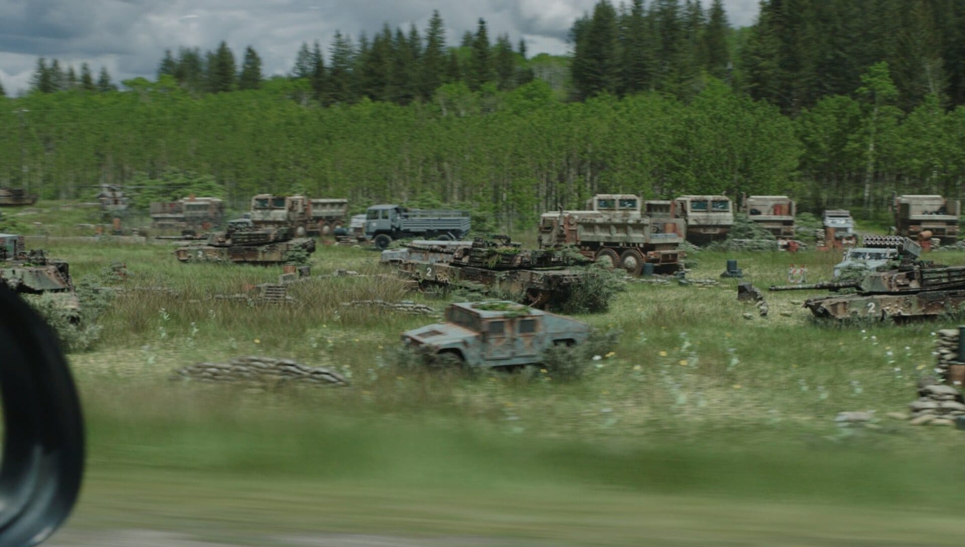 Decaying trucks, tanks, and other army vehicles sit in a grassy field in 'The Last of Us'